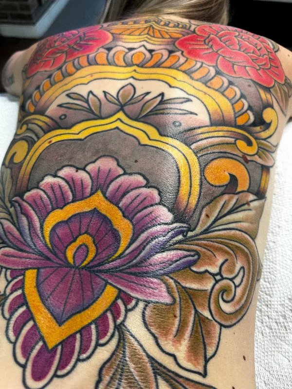 Close detail of colorful floral back tattoo by Castro